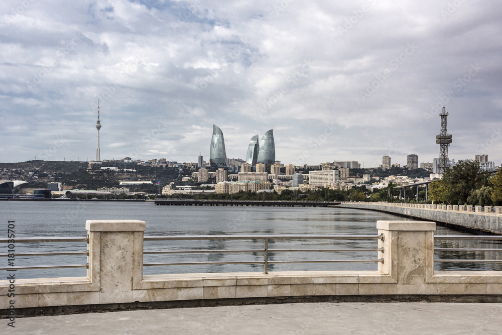 Azerbaijan, Baku: Strolling promenade with cityscape of the capital, Flame Towers, TV tower and cloudy sky in the background.