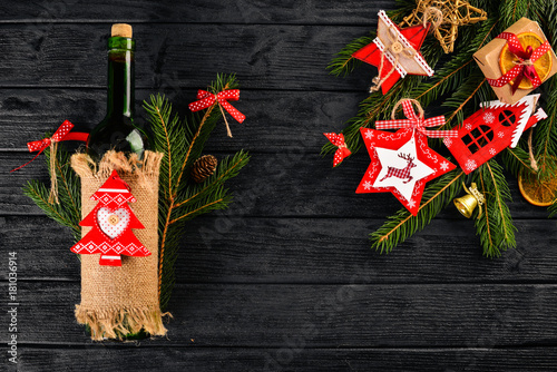Christmas table serving, and a bottle of wine. New Year. Christmas tree and Christmas tree decorations. On a wooden background. Free space for text.