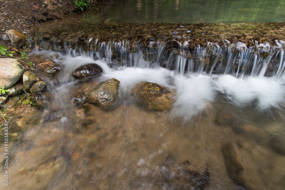 The stream flows through the weir. The stream flows through the weir.