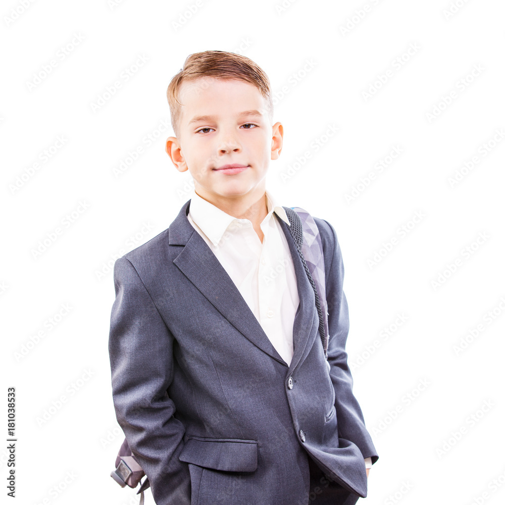 Serious young male student of primary school isolated on white background. Calm and confident schoolboy in suit with backpack on his shoulder