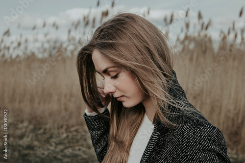 Prertty young woman posing at camera outdoor. Bulrush background. Outdoor. Close up.