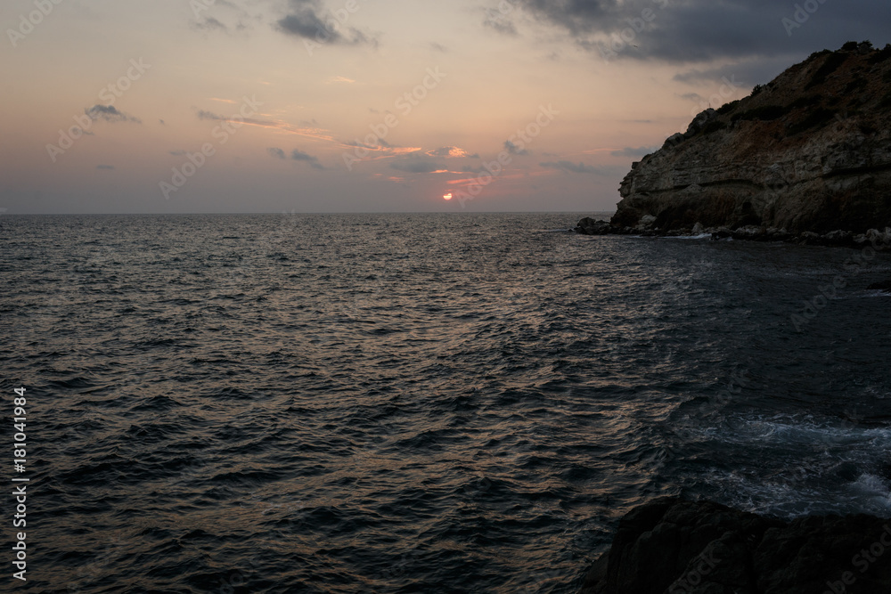  Sunset at the sea. Rocky coast. Mountains and the sea at dusk.