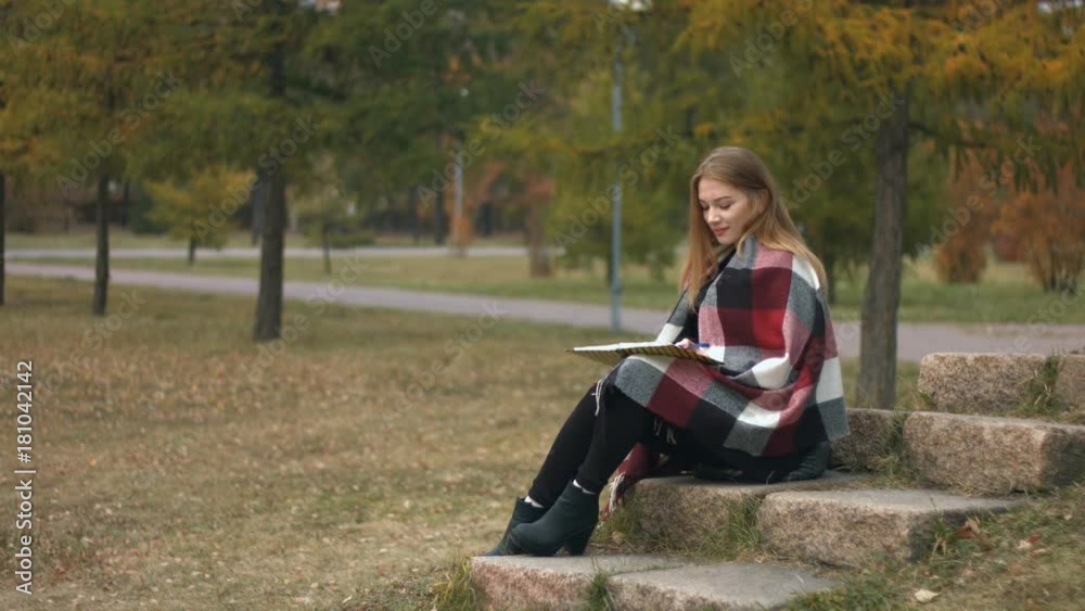 Girl in the autumn park.
Slow motion. A young girl sits on a stone in the park and writes in a notebook. Girl in the autumn park.
Slow motion. A young girl sits on a stone in the park and writes in a notebook.