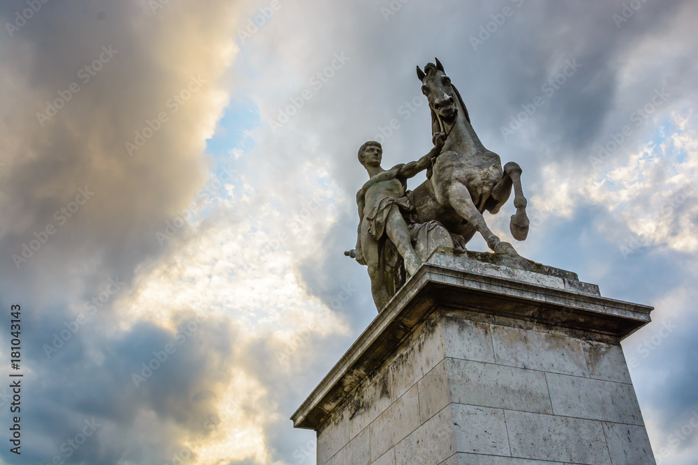 View from below of the equestrian statue of a roman warrior by Louis-Joseph Daumas located on the left bank of the Iena bridge in Paris under a heavy cloudy sky.