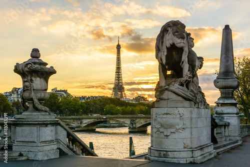 The Eiffel Tower at sunset seen from the Alexander III bridge with a Lion sculpture by Georges Gardet in the foreground. © olrat