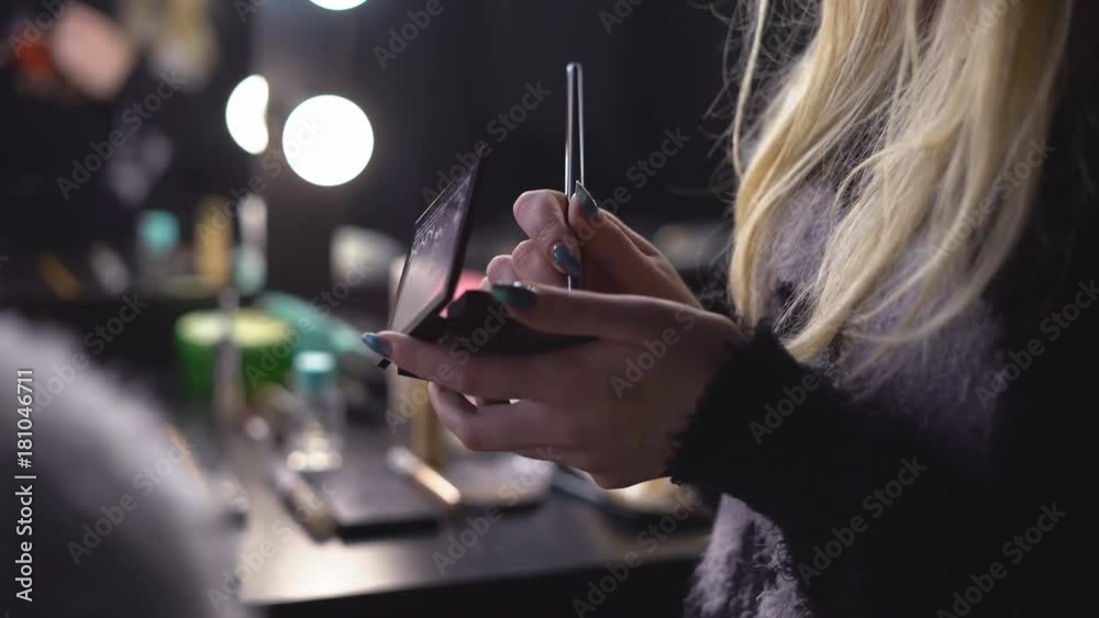 a professional make-up artist girl holds in her hand a pallet with cosmetic means of a shadow for a century / lipstick \ proof-readers. The woman dips the brush in the makeup and applies makeup to the