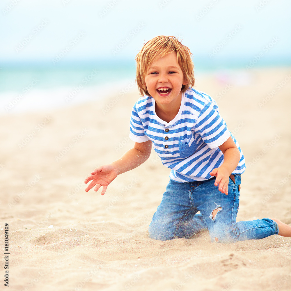 happy, delighted kid, boy having fun , playing in sand on the beach happy, delighted kid, boy having fun , playing in sand on the beach