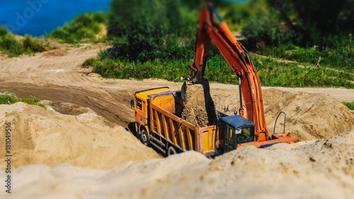 Excavator loading sand into dumper truck