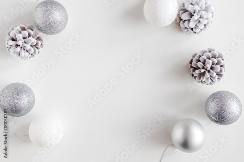 White Christmas background. Frosty pine cones  white  glitter  silver colored decoration balls. Minimalist style. Copyspace for text  overhead  horizontal