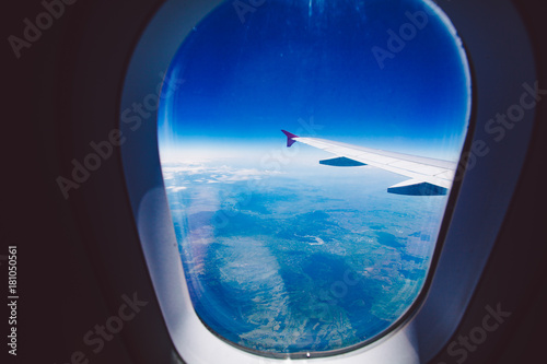 Looking through window aircraft during flight in wing blue sky.