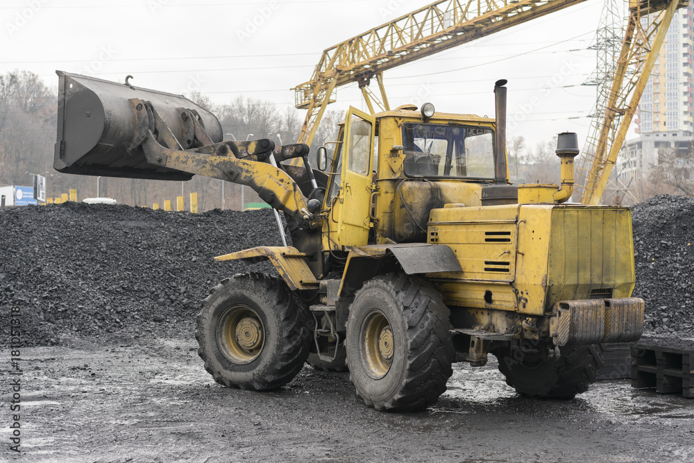 Yellow bulldozer loads black coal