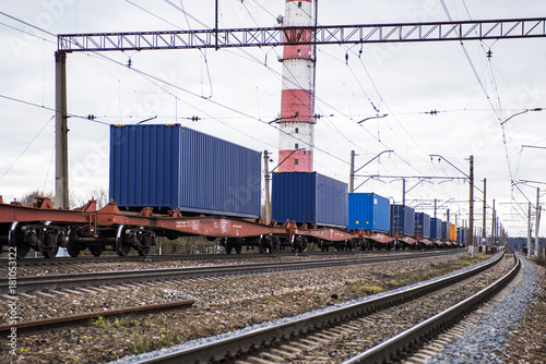 Freight train with containers on the platform is standing on the railroad tracks