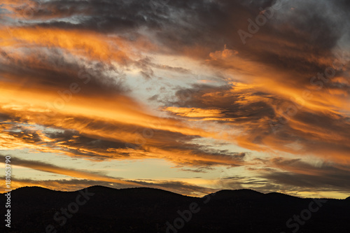 beautiful striped clouds over silhouetted mountains during sunset