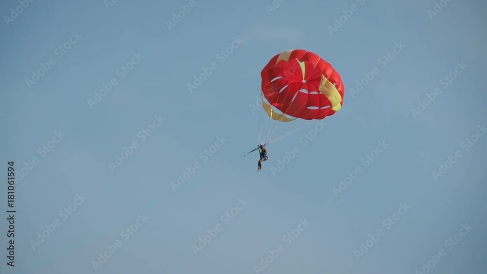 Parasailing. A woman is flying on a red parachute. Parasailing. A woman is flying on a red parachute.