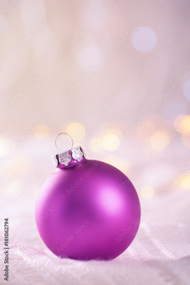 Purple Christmas ball on white lace on light and warm bokeh background Purple Christmas ball on white lace on light and warm bokeh background