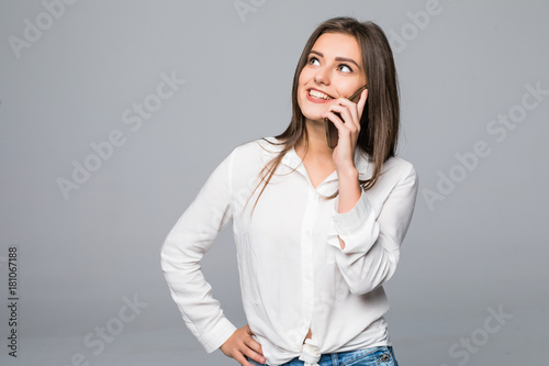 Beautiful attractive casual young woman talking on her mobile phone. Studio shot over gray background. photo