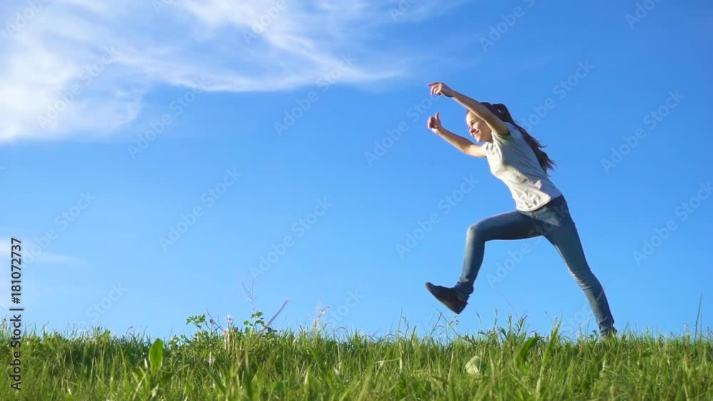 Happy girl running on green grass hill against blue sky Happy girl running on green grass hill against blue sky