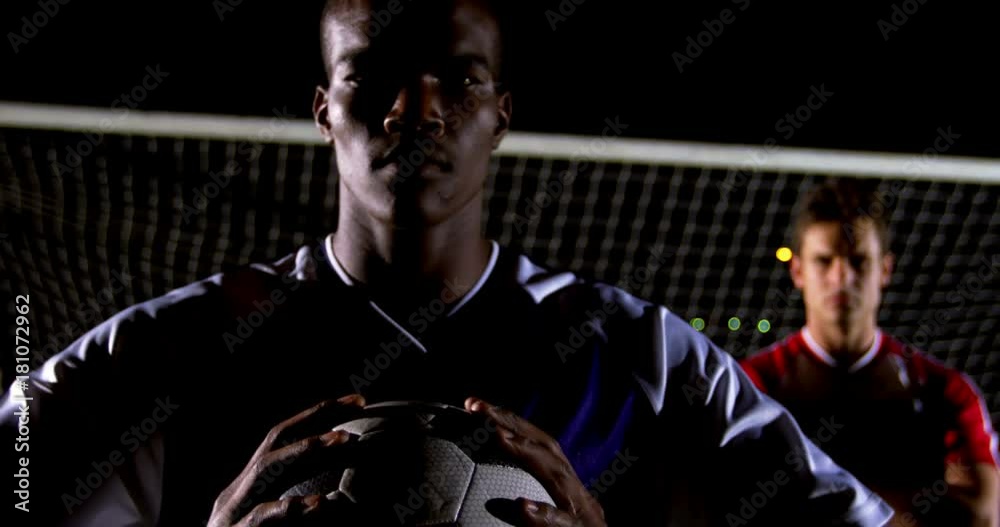 Portrait of confident African American man soccer player holding ball with rival athlete 