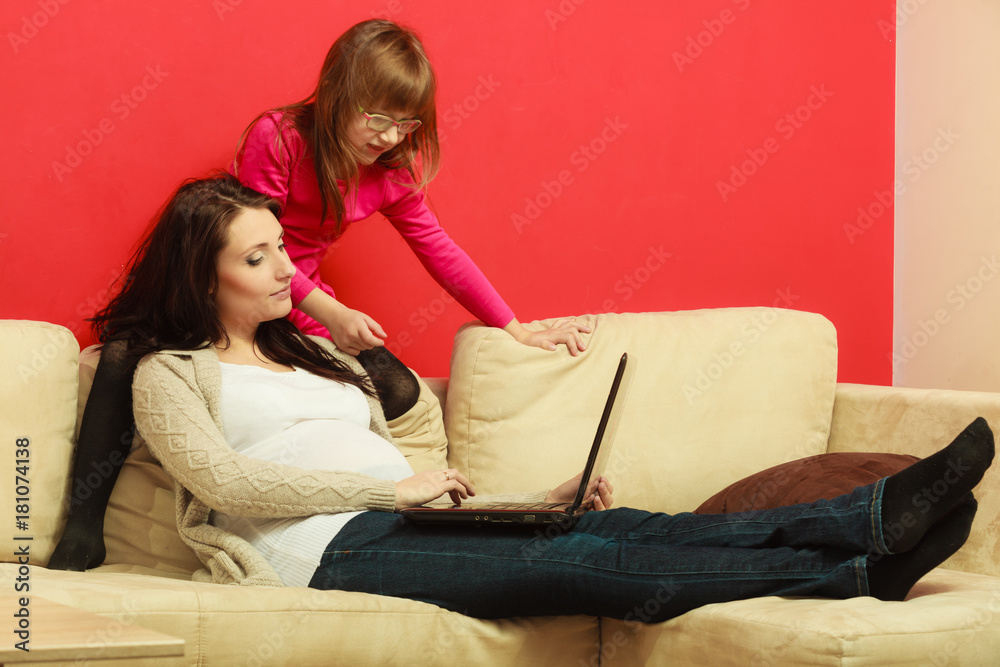 Pregnant woman and daughter sitting with laptop Pregnant woman and daughter sitting with laptop
