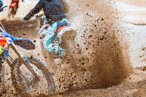 Fototapeta Naklejka Na Ścianę i Meble -  Details of flying debris during an acceleration with mountain bikes race in dirt track in sunshine day time in blurry background. Concept of focus between an accelerate in action sport
