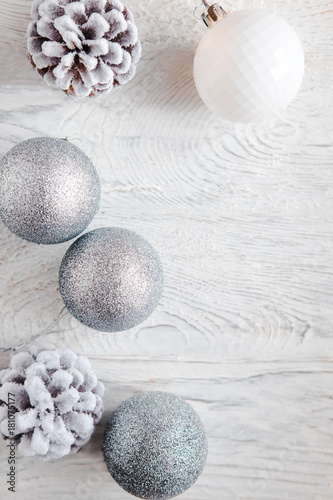 White Christmas background from above. Frosty pine cones, white, glitter, silver colored decoration balls. Minimalist style. Copyspace for text, overhead, horizontal