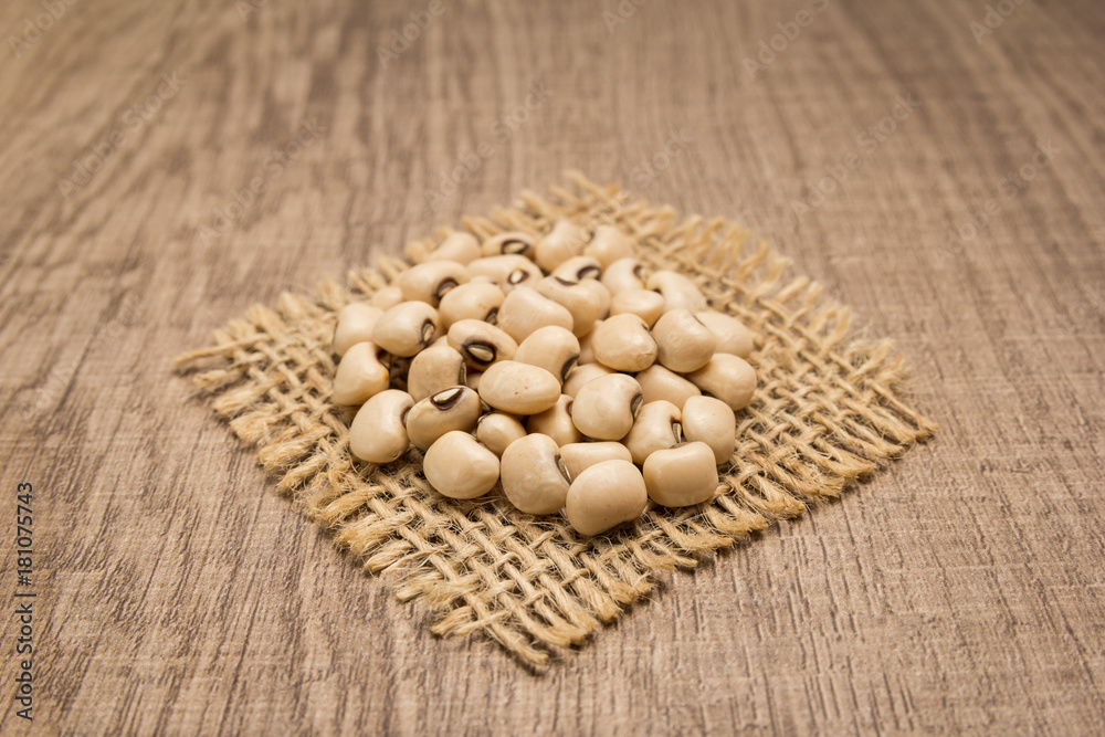 Black Eyed Pea legume. Grains on square cutout of jute. Wooden table. Selective focus. Black Eyed Pea legume. Grains on square cutout of jute. Wooden table. Selective focus.