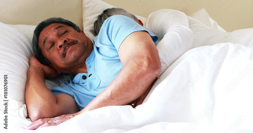 Senior man getting disturbed with woman snoring on bed Senior man getting disturbed with woman snoring on bed