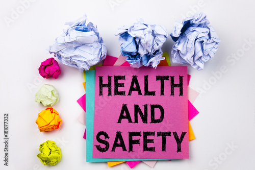 Writing text showing Health and Safety written on sticky note in office with screw paper balls. Business concept for Awareness construction safety on the white isolated background. photo