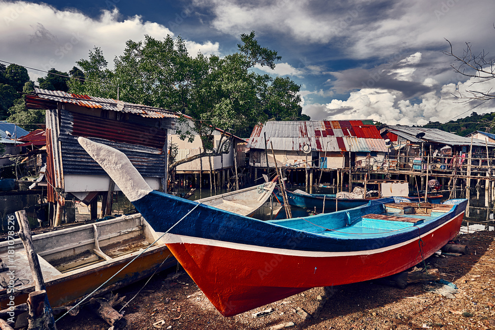 Old colorful asian fishing boats and dramatic sky on the background. Traditional asian fishing village, Langkawi island, Malaysia.