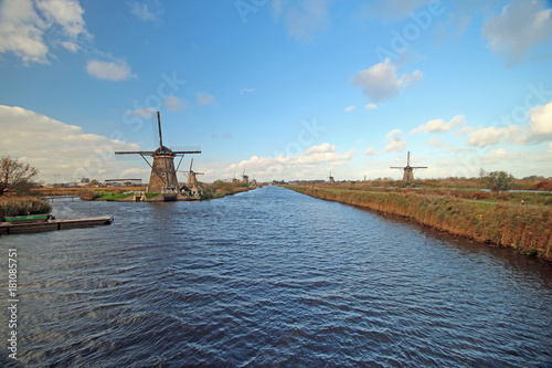 Historical windmills at the Kinderdijk area along a canal in the Netherlands with Blue sky and big white clouds	