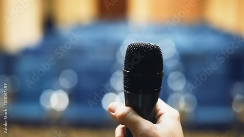 closeup view male hand using microphone blur blue background rehearsal oral culture speeches fear public speech oration declamation declaim man holding mic transmitter mike audience nobody inside