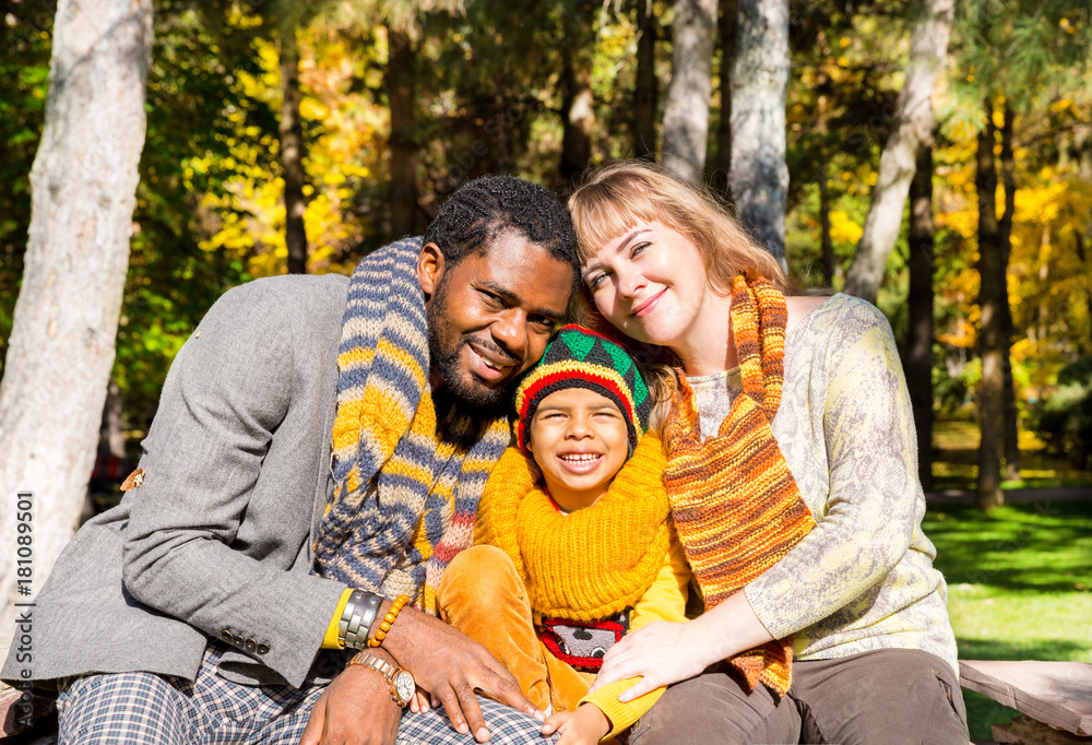 Happy family in autumn park. African American family: black father, mom and child boy on nature in fall.