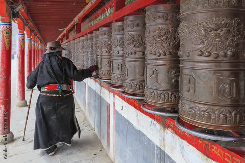Valokuvatapetti Yushu, China - November 3, 2017: Tibetan people spinning the prayer wheels around Mani Temple (Mani Shicheng) a famous landmark in the Tibetan city of Yushu (Jyekundo), Qinghai, China