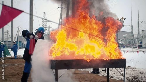 Worker with a fire extinguisher extinguishes the fire slow motion