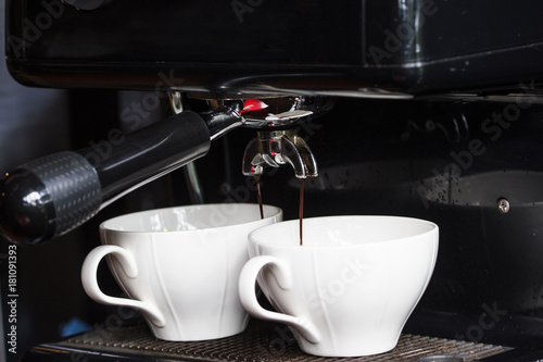 Coffee machine making two cup of fresh espresso background. Espresso is a coffee brewed by forcing a small amount of nearly boiling water under pressure through finely ground coffee beans.