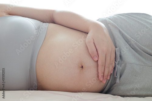 Beautiful pregnant woman holds hands on the bed,Concept of pregnancy, maternity, health care