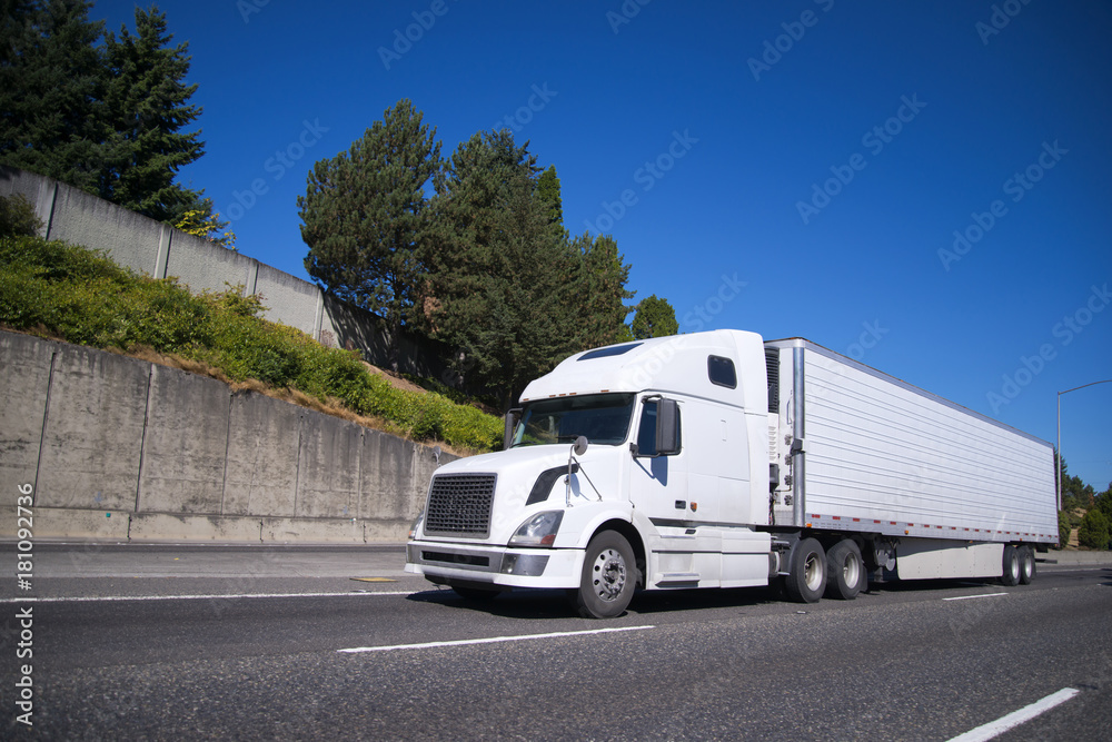 Big rig semi truck with reefer semi trailer going on highway with commercial cargo for delivery Big rig semi truck with reefer semi trailer going on highway with commercial cargo for delivery