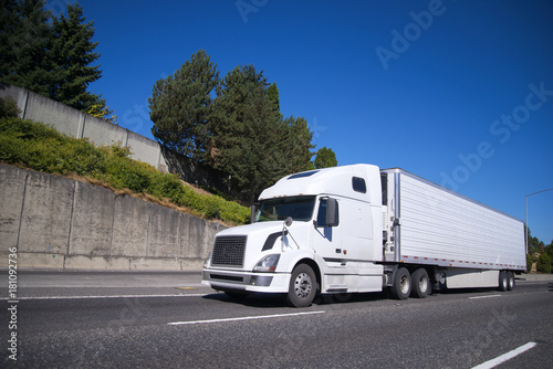 Big rig semi truck with reefer semi trailer going on highway with commercial cargo for delivery photo