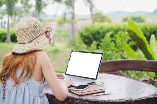 Young cute brown hair woman wearing cream hat using laptop notebook for education and writing text in a natural park, Technology social media concept.