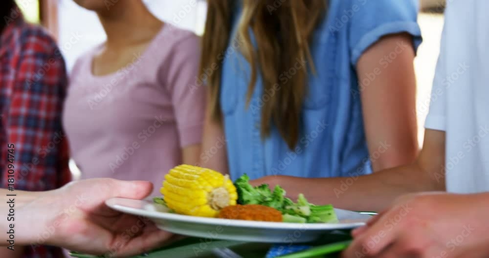 Worker serving meal to schoolkids Worker serving meal to schoolkids