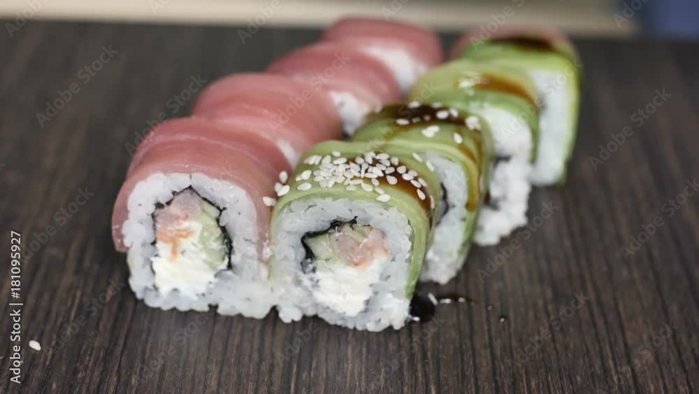 Close up of chopsticks holds sushi maki gunkan roll over a plate or platter set. Served in Japanese bar restaurant. Top view, flat lay. Food background. copy space. Close up of chopsticks holds sushi maki gunkan roll over a plate or platter set. Served in Japanese bar restaurant. Top view, flat lay. Food background. copy space.