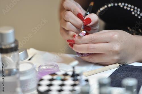 woman getting manicure, colorful artificial nails on shelves in beauty shop, woman hand while process of manicure in nail shop. Beautiful concept.