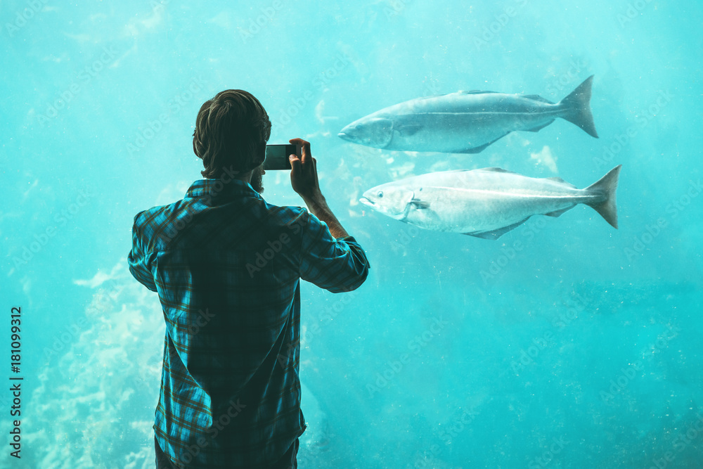 Man taking photo by smartphone of fish in big aquarium Travel Lifestyle concept modern technology