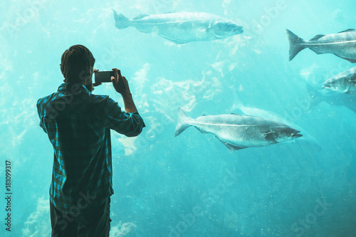 Man tourist taking photo by smartphone of big aquarium fish Travel Lifestyle concept modern technology