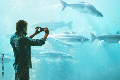 Man taking photo using smartphone of fish in big aquarium Travel Lifestyle concept modern technology