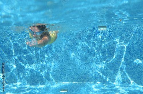 Young girl swimmer swimming under water in pool and has fun, teenager diving underwater, family vacation, sport and fitness concept 