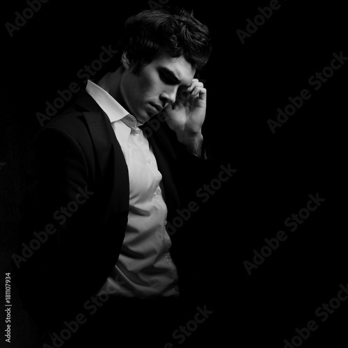 Thinking depression charismatic man looking down on dark shadow dramatic light background. Closeup black and white portrait. Art