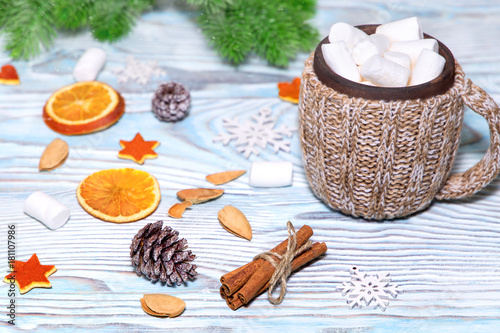Cup of hot Chocolate drink with marshmallows  cinnamon sticks  dry oranges  cones and fir tree on light blue wooden background. Winter christmas holiday background. Flat lay