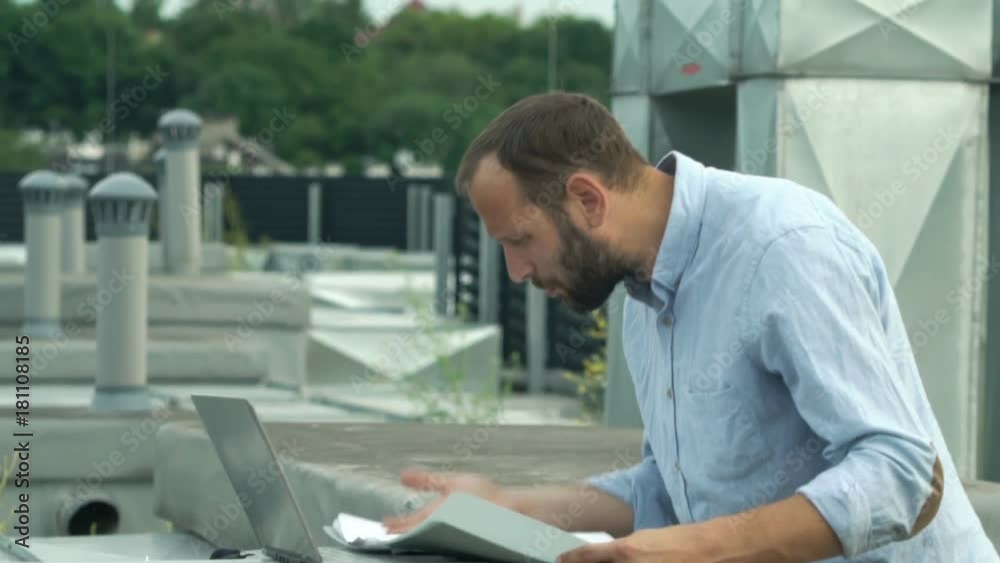 Upset, unhappy man with laptop and documents checking air conditioning plan on roof
Upset, unhappy man with laptop and documents checking air conditioning plan on roof