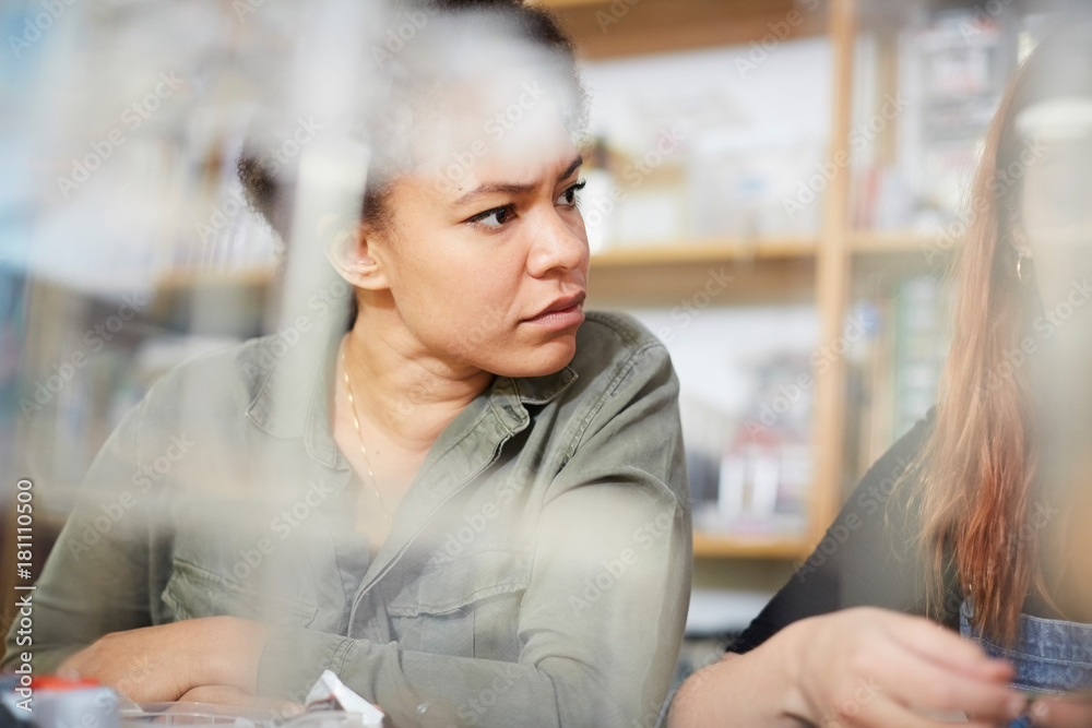 Mid adult technician looking away while sitting by female colleague at workshop Mid adult technician looking away while sitting by female colleague at workshop